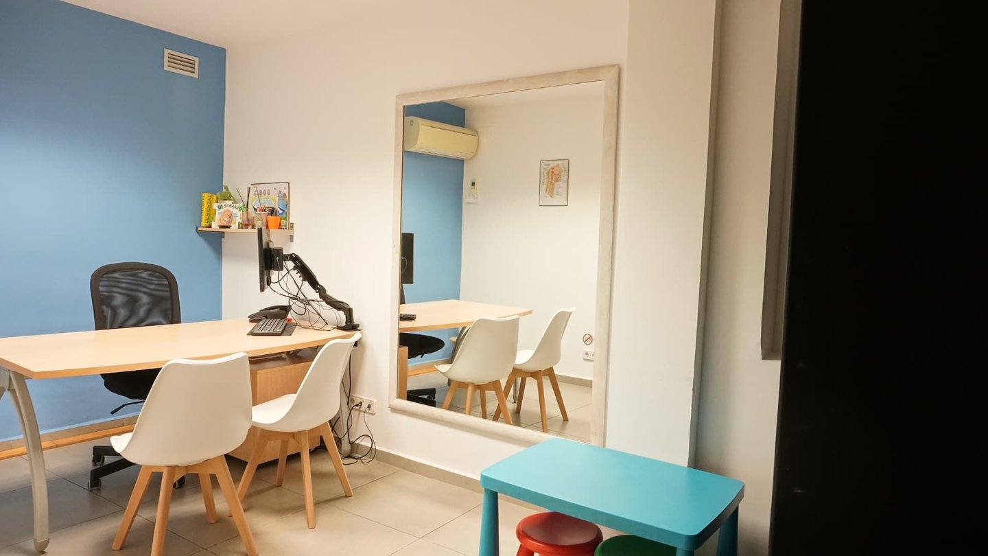 Espejo de la sala de logopedia reflejando la mesa de trabajo