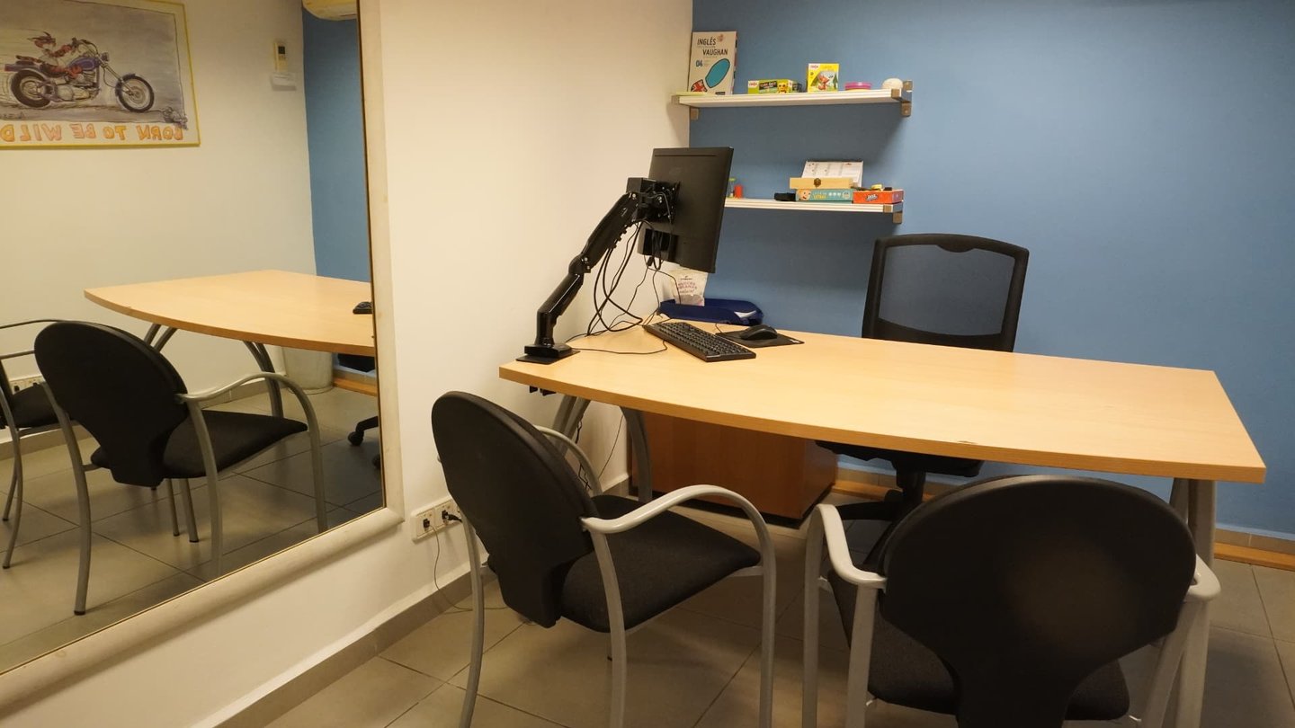 Sala de reeducación psicopedagógica con mesa de trabajo y material didáctico en la estantería