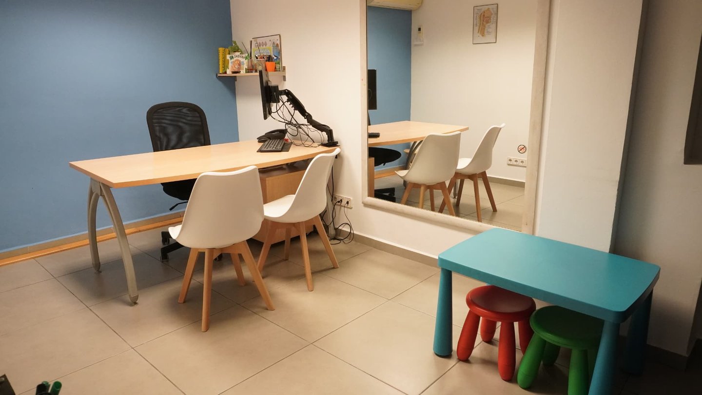 Sala de logopedia con mesa de trabajo, espejo y material infantil